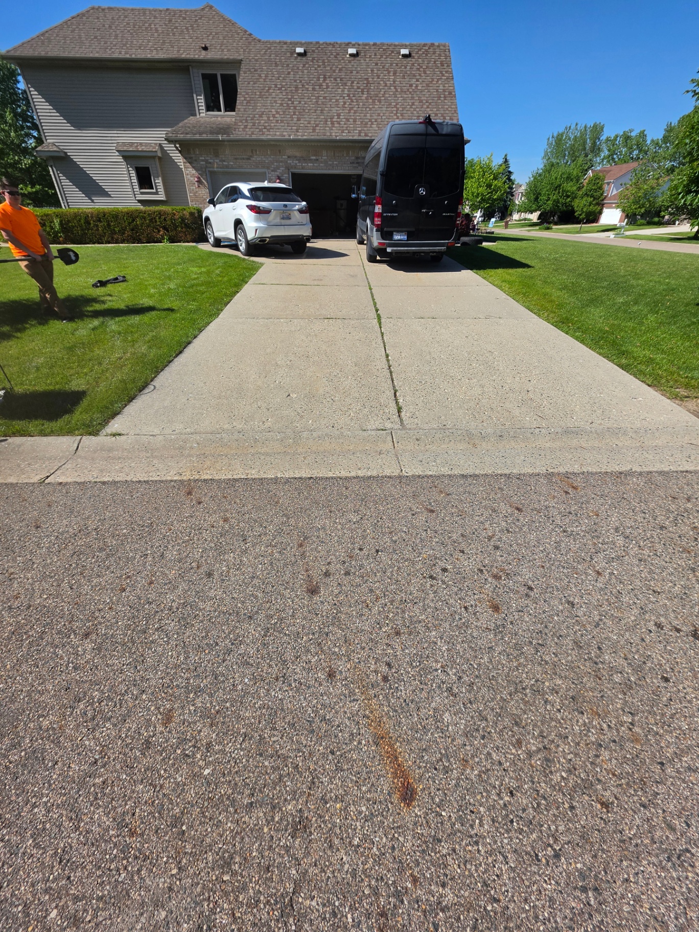 Plain concrete driveway with grass growing right up to the edges before landscaping