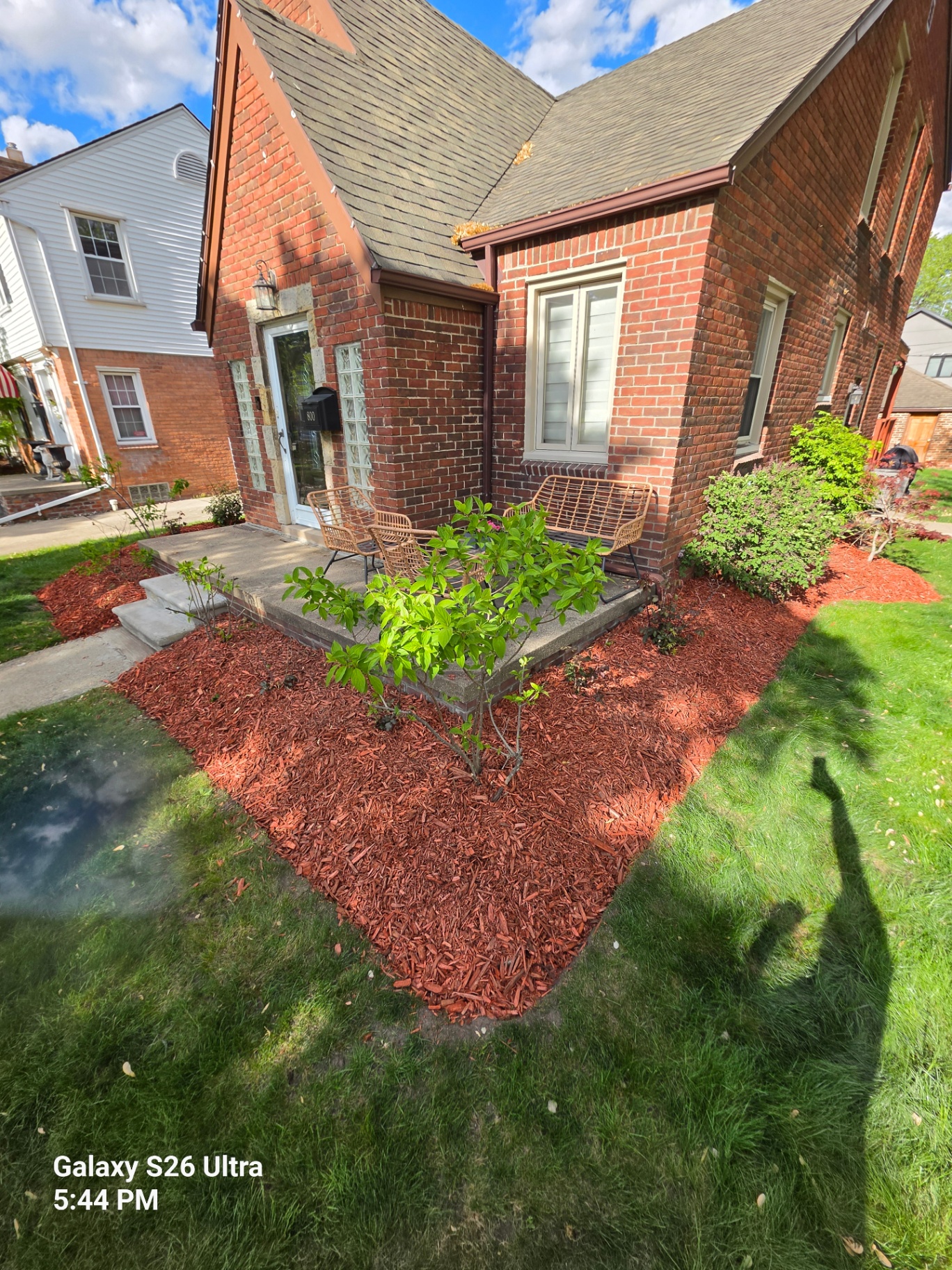Same brick home with a clean, freshly mulched red bed wrapping the front porch
