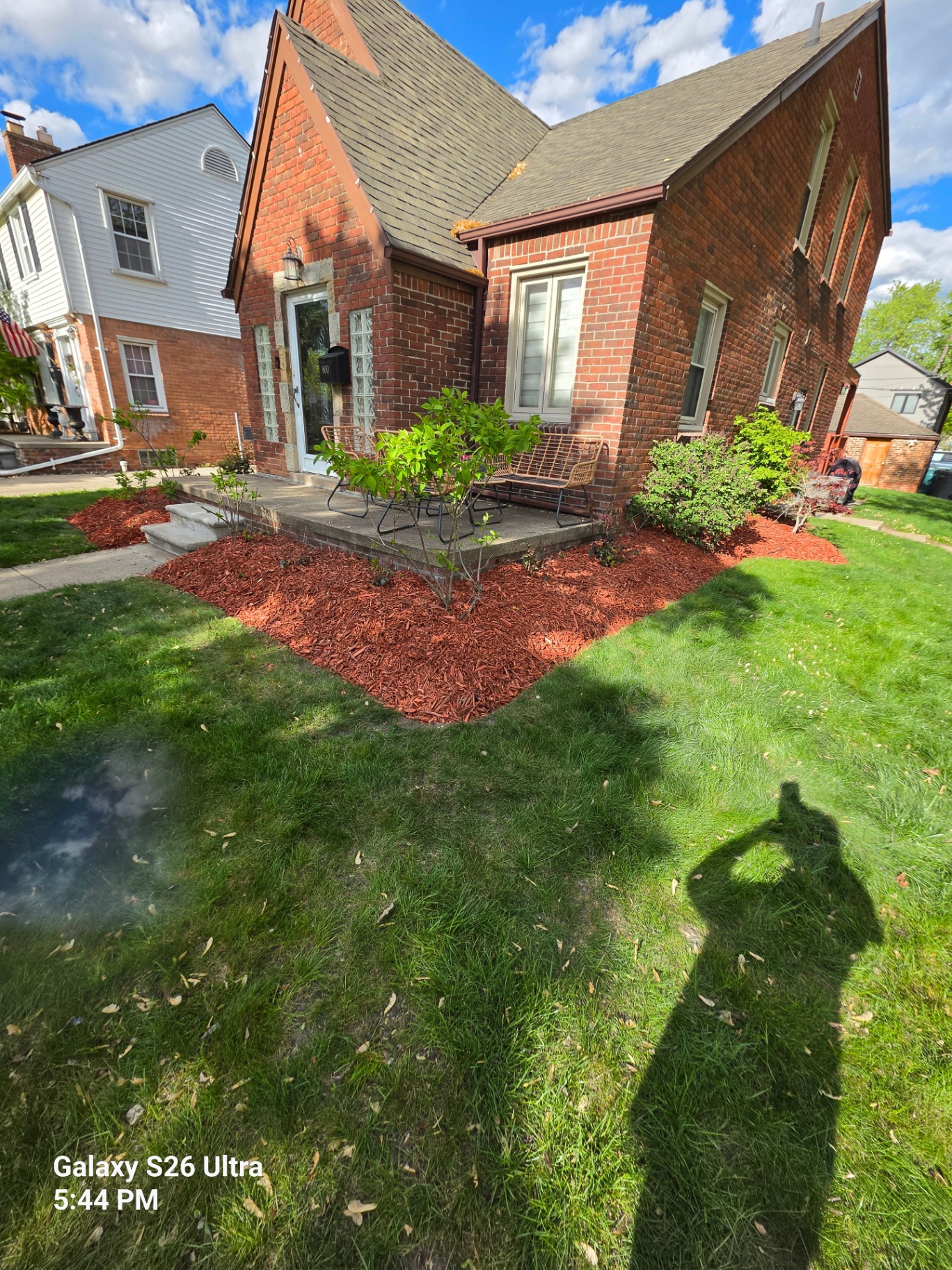 Front yard landscape bed refreshed with new red mulch around a brick home