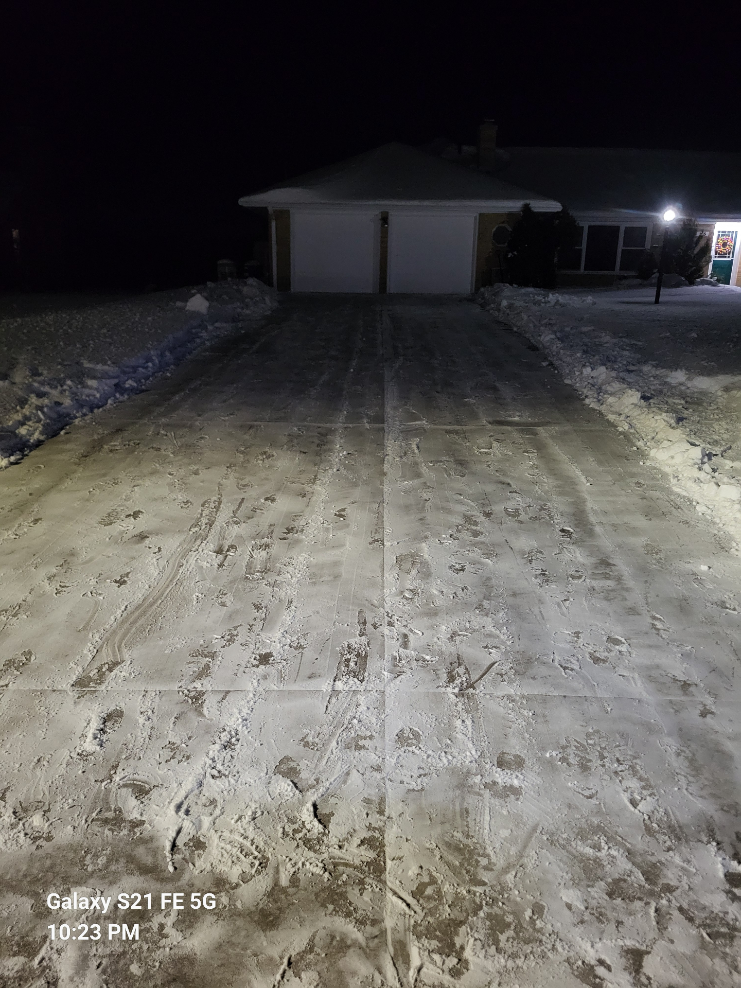 Same driveway cleared down to the concrete with snow banked along both sides