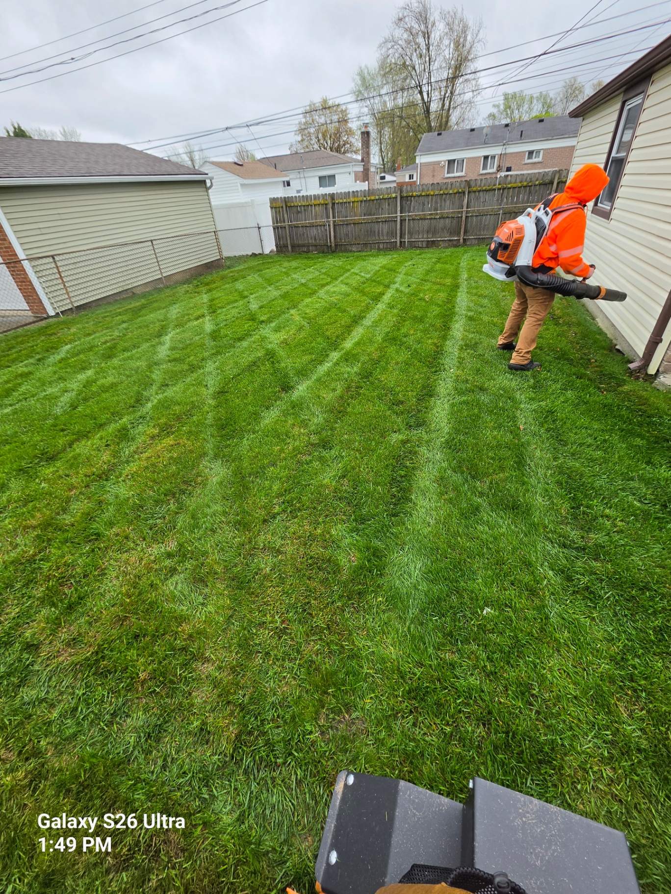 Crew member using a blower in a freshly cut backyard