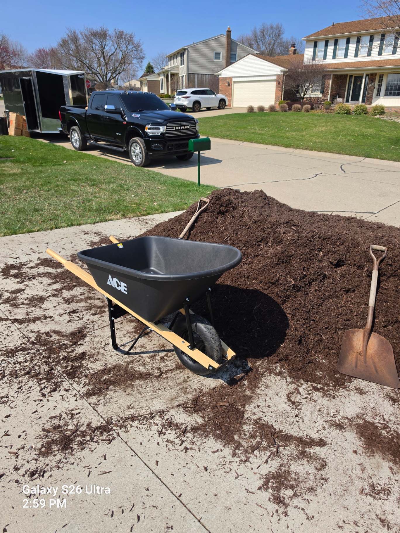 Mulch pile, wheelbarrow, and tools staged for a landscaping refresh